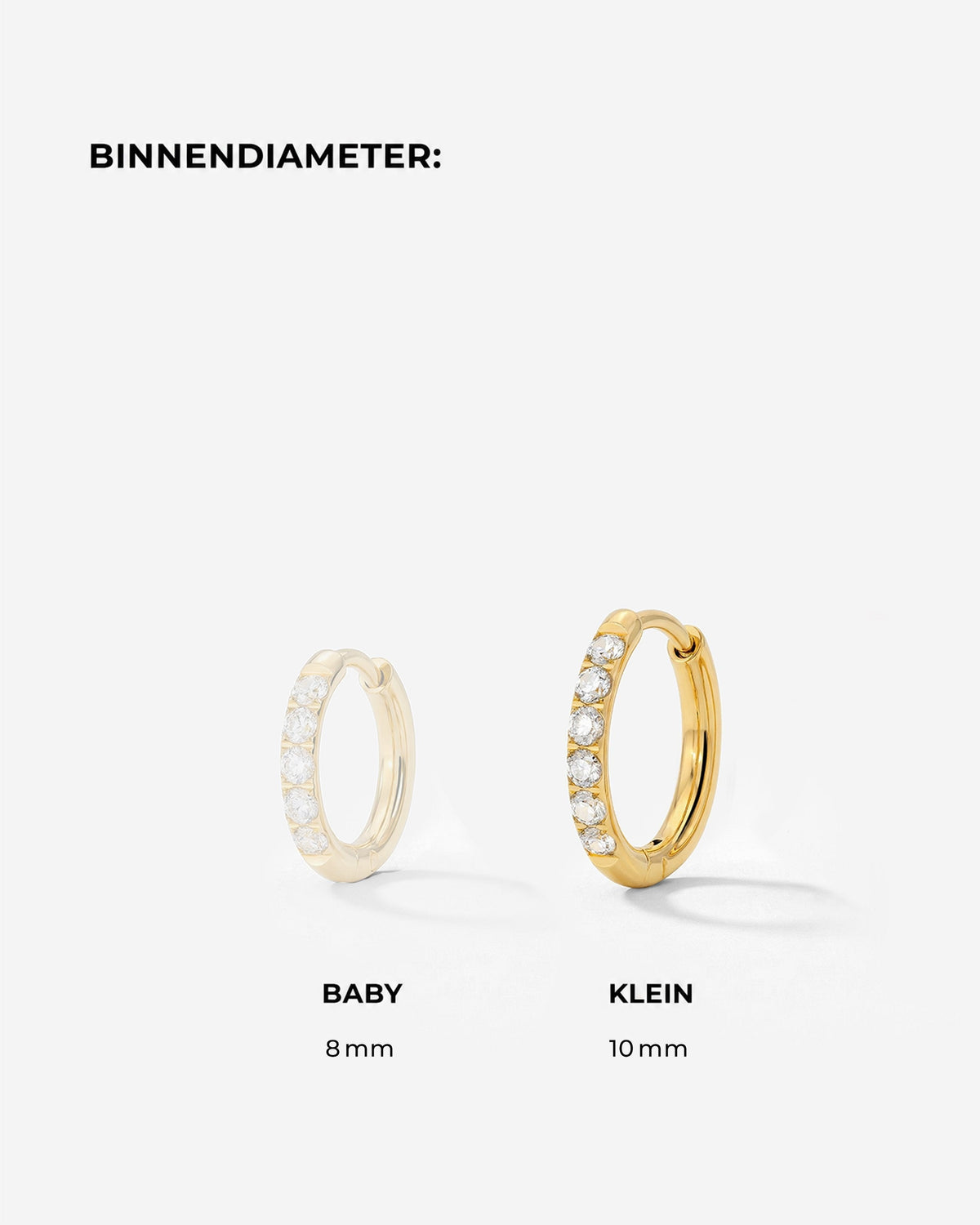 Maatvergelijking van twee gouden oorringen met zirkonia, waarbij de grotere ring in beeld is uitgelicht