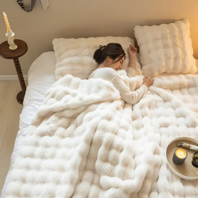 Vrouw slaapt onder een crèmewitte pluizige deken met kussens, naast een bijzettafel met kaars en een dienblad 11
