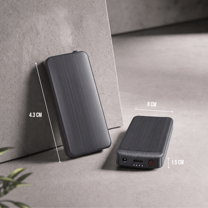 Twee zwarte powerbanks op betonnen ondergrond, met afmetingen aangegeven en de poorten en aan-uitknop zichtbaar