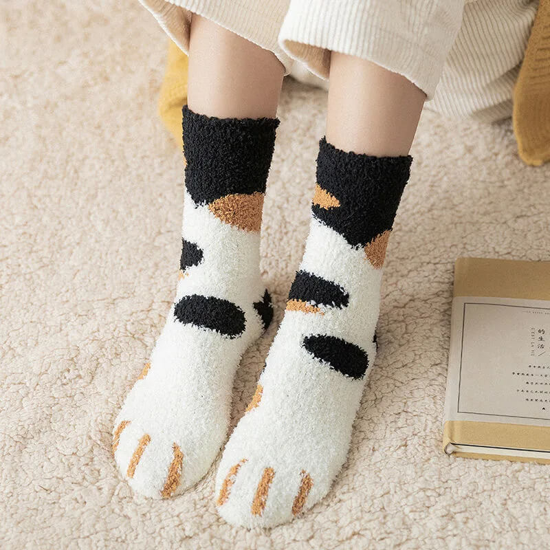 Gedragen witte pluchen sokken met zwarte en oranje vlekken en oranje geborduurde kattenpoottenen