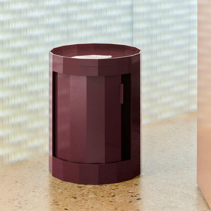 Bordeauxrode ronde kast met gesloten deur op een terrazzo plank voor geribbeld glas 49