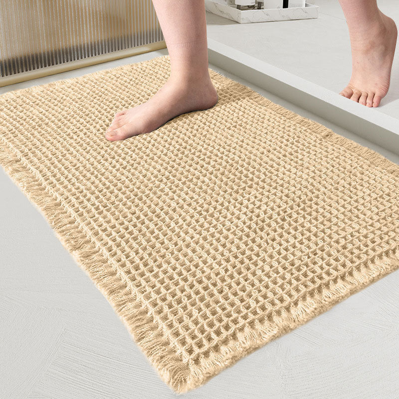 Close-up van de wafelmat in zandkleurig crème, met een blote voet erop in de badkamer