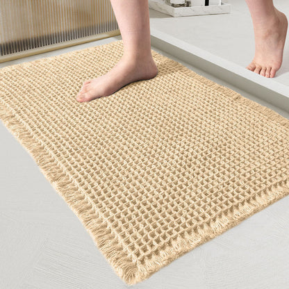 Close-up van de wafelmat in zandkleurig crème, met een blote voet erop in de badkamer