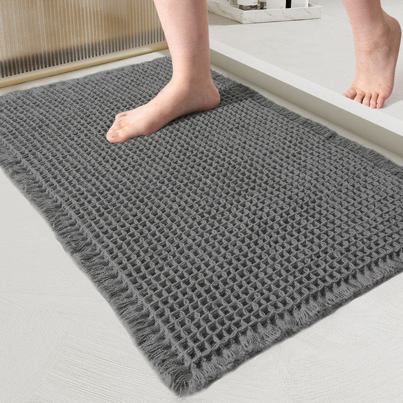 Close-up van de wafelmat in donkergrijs, met een blote voet erop in de badkamer