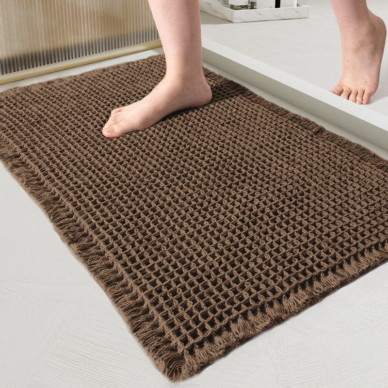 Close-up van de wafelmat in donkerbruin, met een blote voet erop in de badkamer