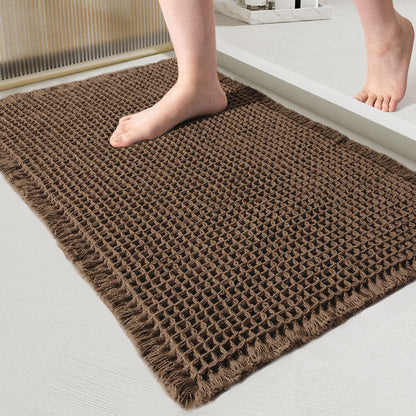 Close-up van de wafelmat in donkerbruin, met een blote voet erop in de badkamer