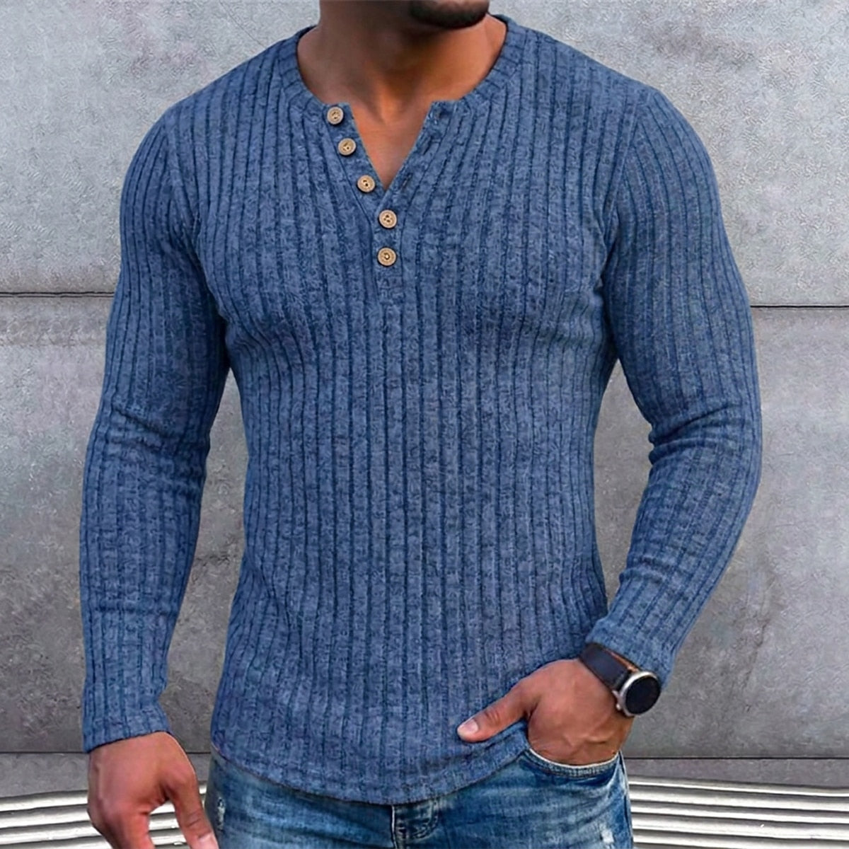 Torso van een man in het blauwe geribbelde shirt met hand in de zak tegen een betonnen muur, detail