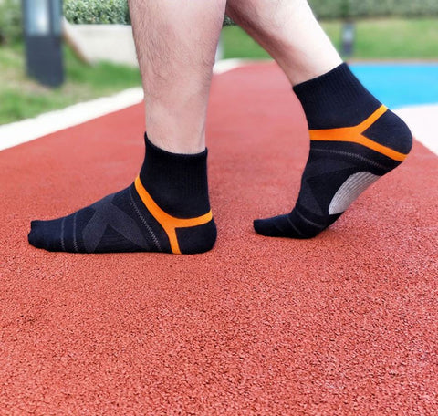 Zwarte sokken met oranje band op een rode atletiekbaan, zonder schoenen