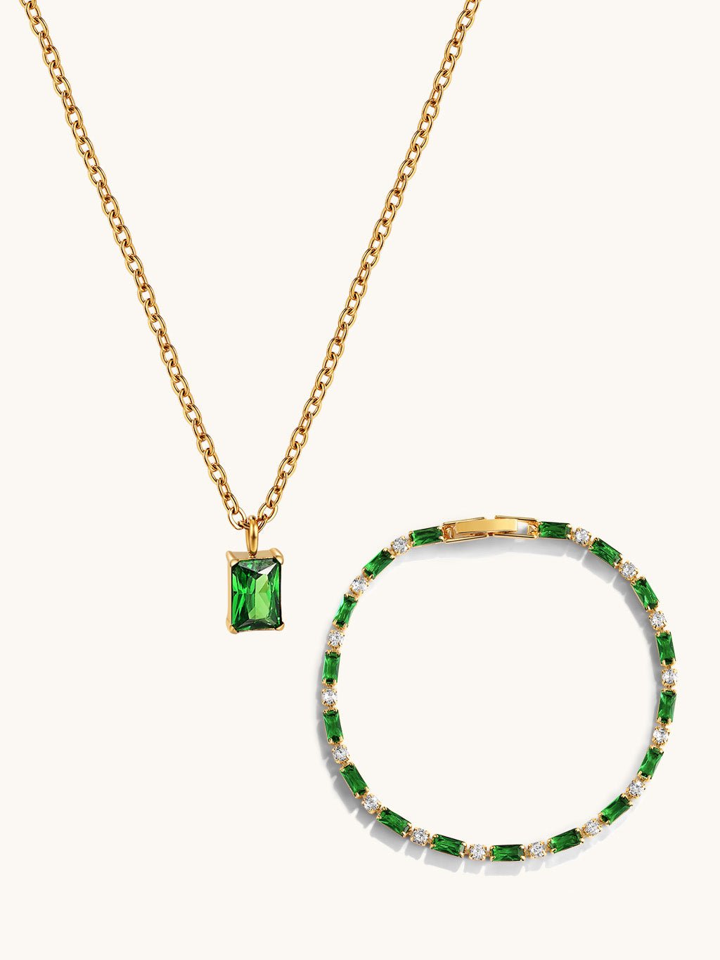 Flatlay van de gouden halsketting met groene rechthoekige hanger en de armband met groene en heldere stenen