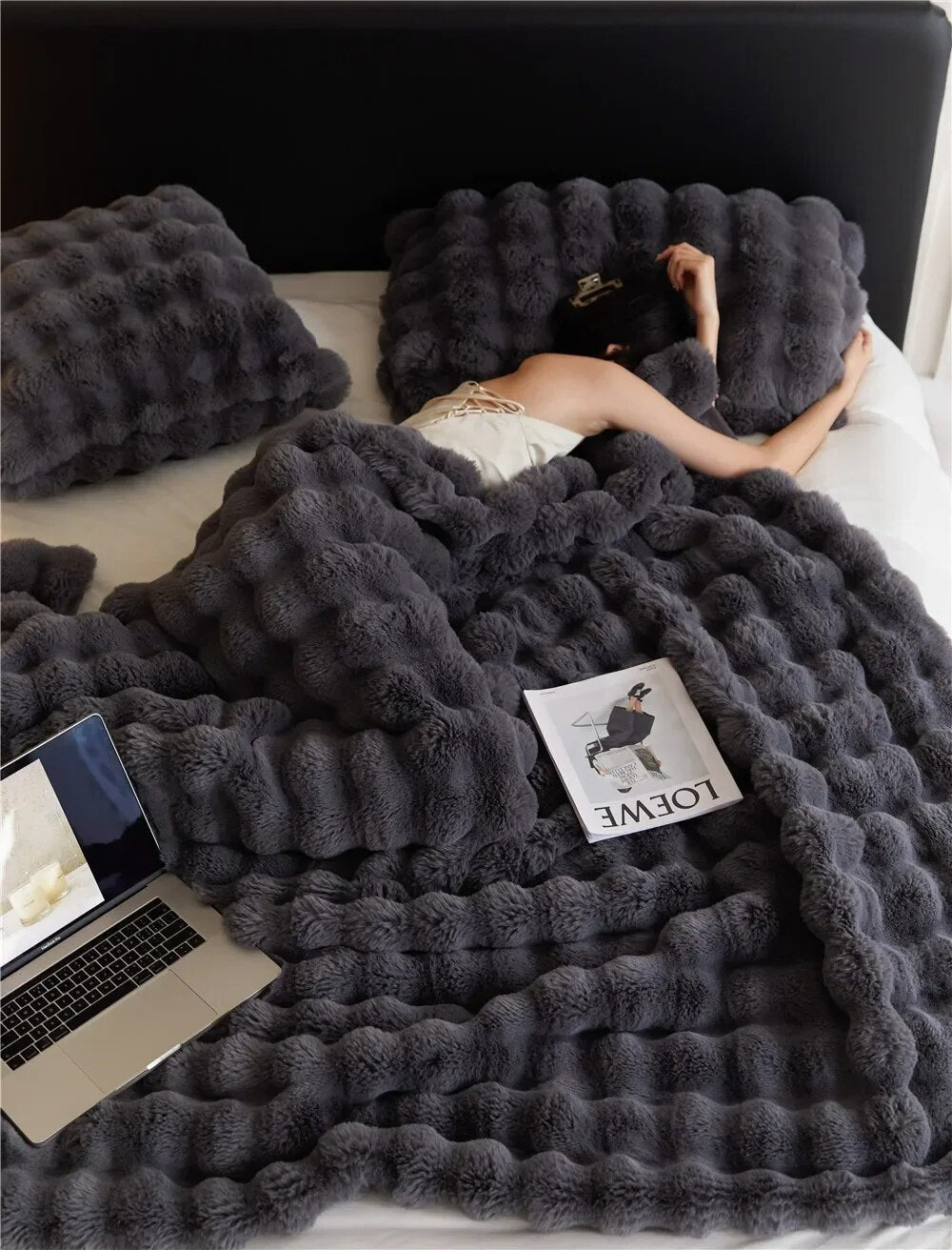 WarmWool deken in donkergrijs over een bed, detail