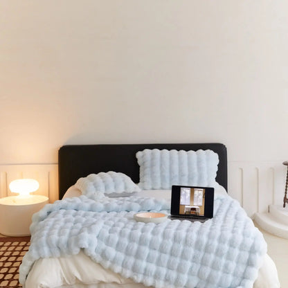 WarmWool lichtblauwe deken op een bed, detail