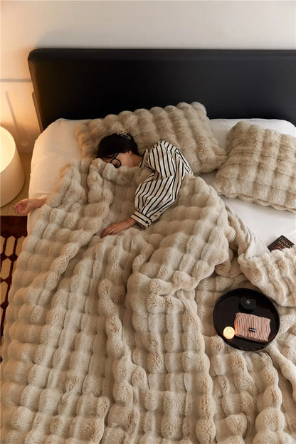 Slapende vrouw in gestreepte pyjama onder een beige pluizige deken met bolletjespatroon, op een bed met kussens 1