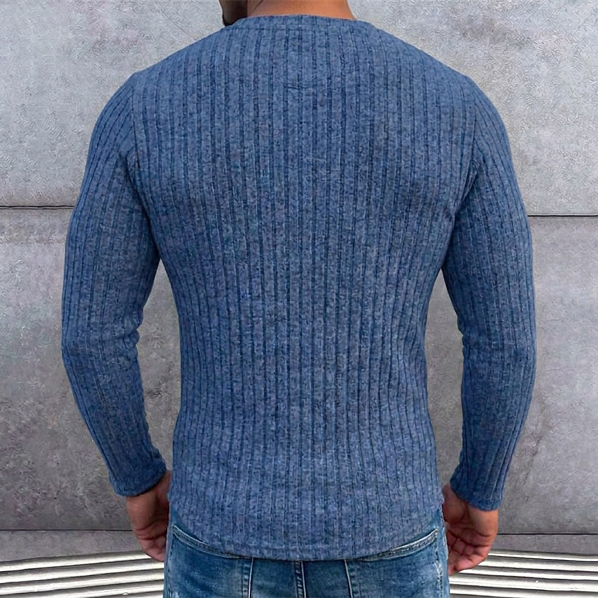 Achterkant van het blauwe geribbelde shirt gedragen door een man voor een betonnen muur, detail